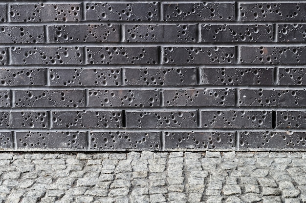 Pared de ladrillo oscuro moderno con suelo de pavimento gris