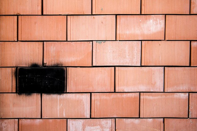 Pared de ladrillo rojo con una pieza negra