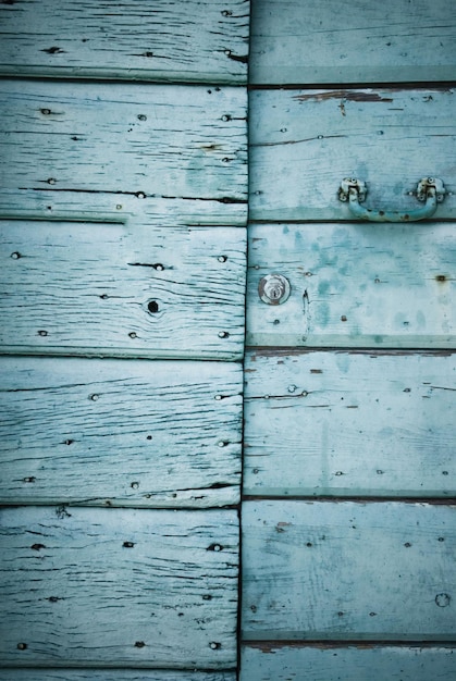 Una pared de madera azul con un asa de metal y un pomo de metal.