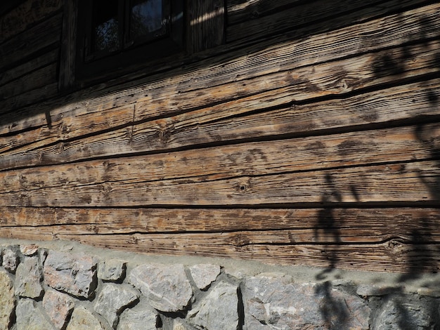 Pared de madera de troncos de una antigua casa de pueblo Fundación de adoquines Métodos antiguos de construcción de edificios residenciales