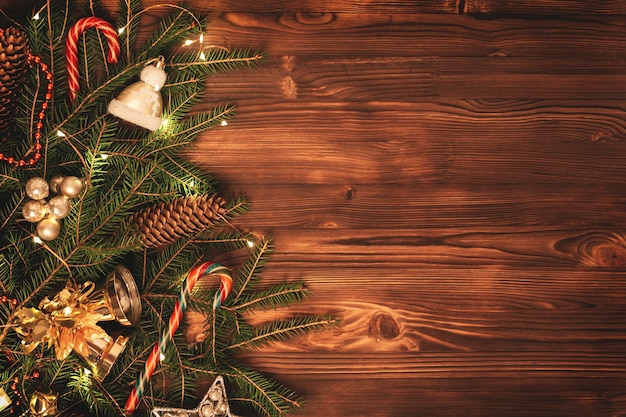 Pared de Navidad con espacio de copia. Ramas de abeto festivamente decoradas sobre una tabla de madera de color marrón oscuro.