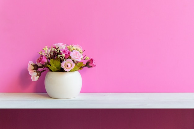 Pared rosada con la flor en la madera blanca del estante, copie el espacio para el texto. Concepto de naturaleza muerta