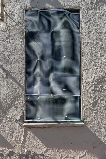 Una pared con una ventana con reja de plástico blanco.