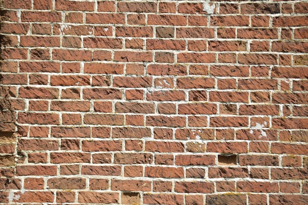 Una pared de viejos ladrillos agrietados con una superficie desgastada y descolorida Ladrillo restaurado de una casa antigua