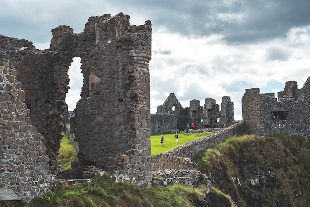 Parede aproximada do castelo dunluce, agora destruído, da Irlanda do Norte, as ruínas sob o céu nublado,