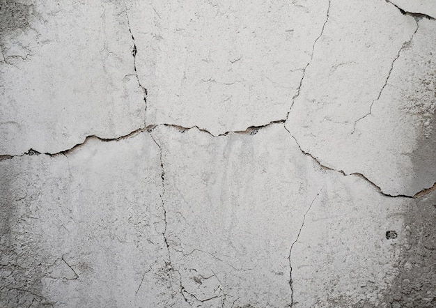 Parede branca de concreto rachado coberta com textura de cimento cinza como fundo