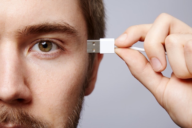 Parede de homem bonito, conceito de negócio, close-up, retrato, segurando usb perto do cérebro.