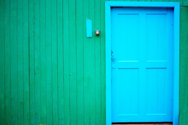 Parede de madeira de cor verde com porta azul