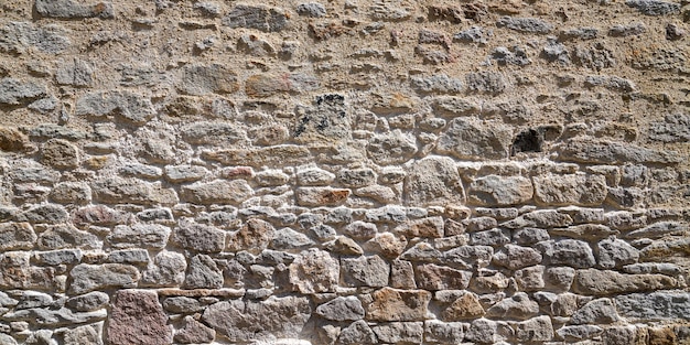 Parede de pedra escura antiga de fundo de fachada de pedras horizontais de tijolos medievais