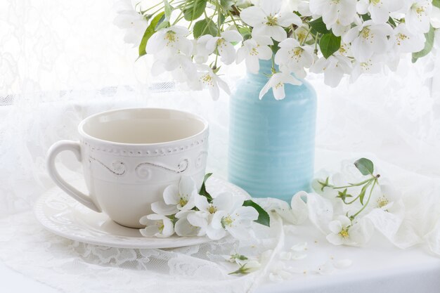 Parede de primavera com flor de cerejeira e xícara de chá na mesa de madeira