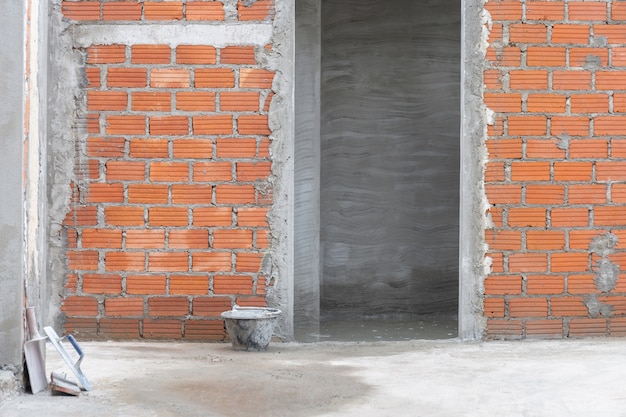 Parede de tijolo vermelho com entrada no local de construção de edifício residencial