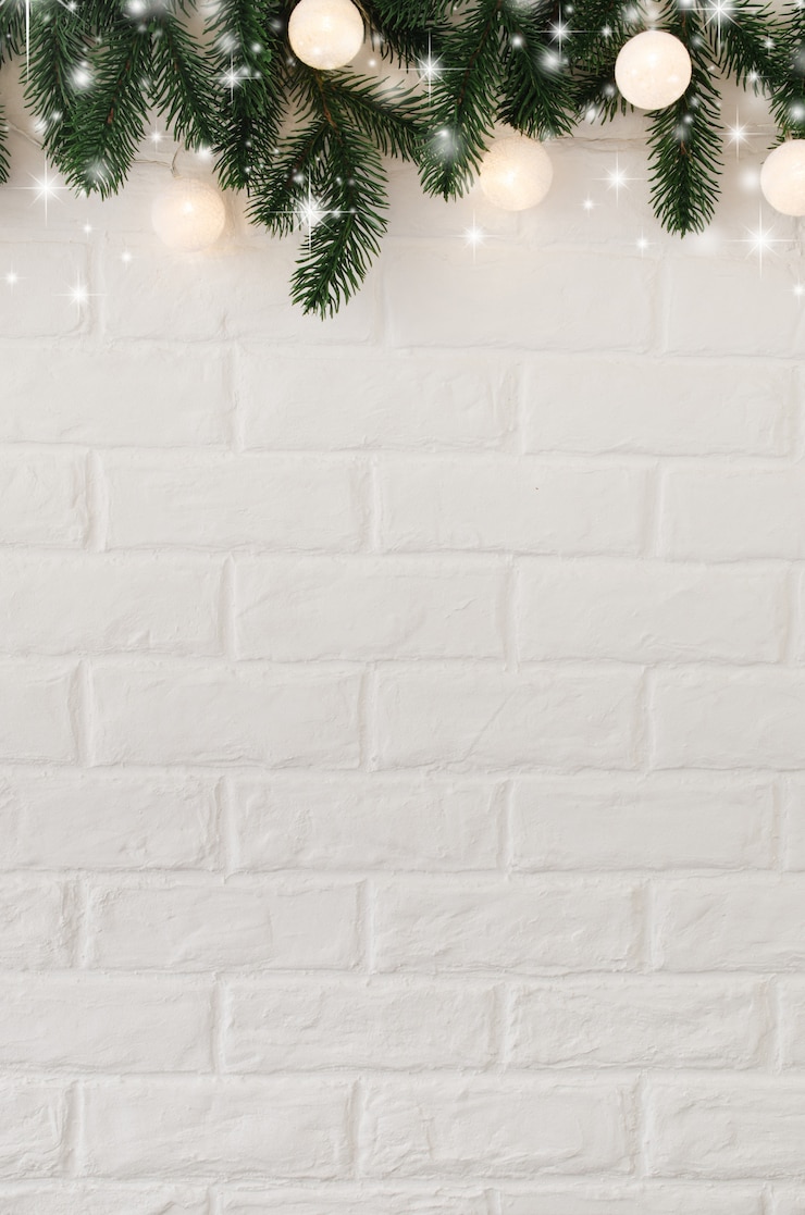Foto parede de tijolos brancos com galhos de pinheiro e luzes de natal em forma de bolas brancas.