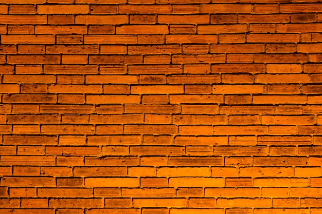 Parede de tijolos de superfície com luz de fundo laranja.