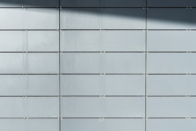 Parede do edifício moderno revestido com painéis frontais com sombra. Fundo arquitetônico abstrato