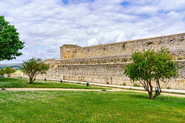 Parede exterior do castelo de Zamora em frente ao parque de grama verde e flores coloridas