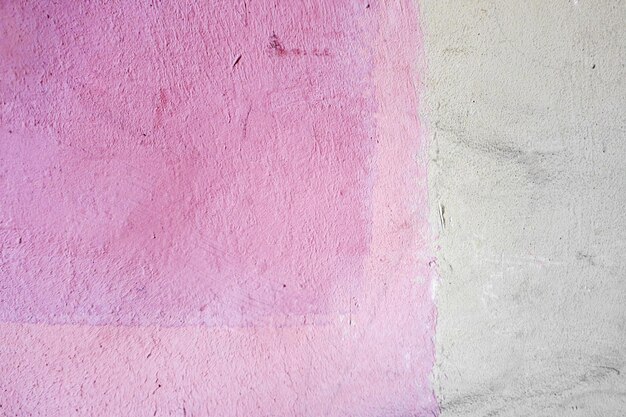 Parede rebocada coberta com tinta rosa branca irregular A parede de uma casa da cidade Fundo rosa