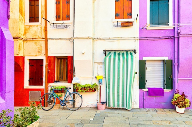 Las paredes de colores tradicionales de las casas antiguas comunes con macetas y la bicicleta cerca de la puerta de entrada en la isla de Burano. Venecia. Región de Veneto en Italia.