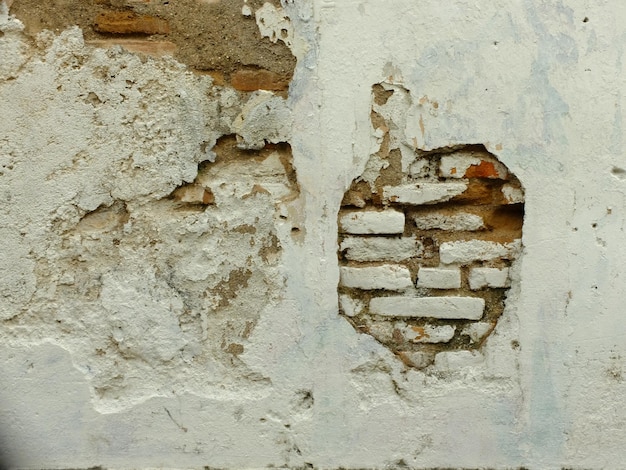 paredes de cimento branco descascando na superfície. tijolos entre as paredes quebradas. casa abandonada.