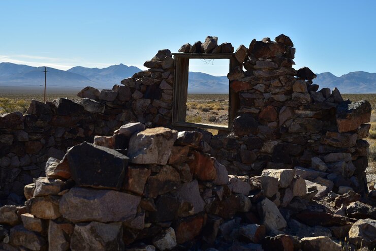 Foto las paredes en deterioro de una casa de piedra abandonada en el desierto de mojave con vistas a las montañas en el marco de la ventana