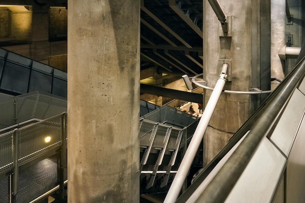 Paredes e tubos de concreto e aço na estação de trem subterrânea de Westminster, pessoas desfocadas descendo escadas à distância - arquitetura futurista