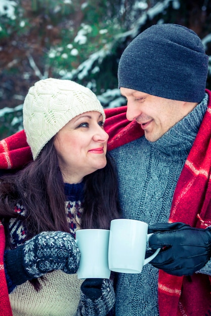 Pareja abraza y sostiene tazas de café