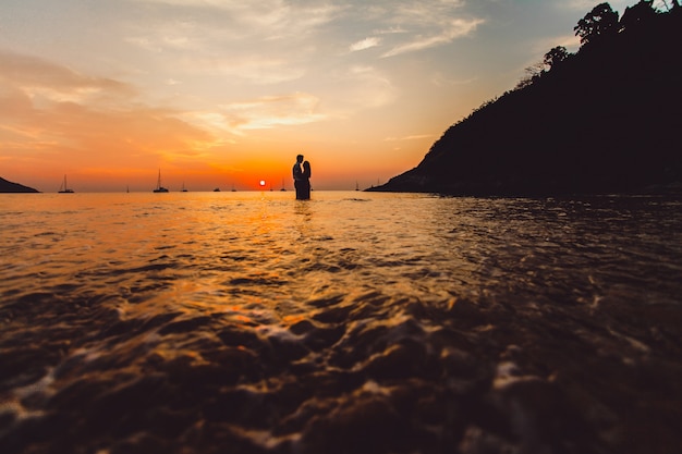 Pareja abrazada en la playa al atardecer