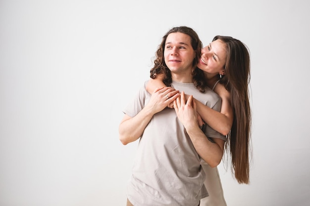 Foto pareja abrazada sobre fondo de pared blanca hombre y mujer enamorados en casa