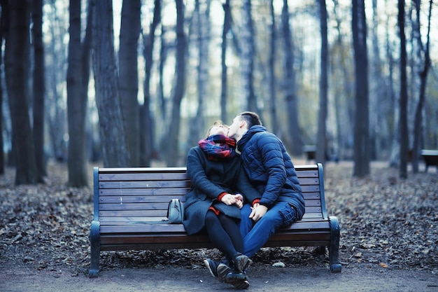 pareja abrazándose en un banco en invierno