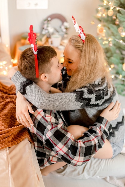 Pareja abrazándose en casa en adornos navideños