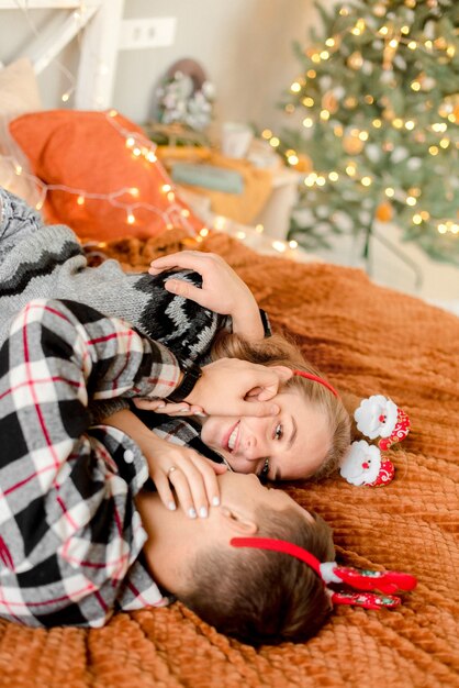 Pareja abrazándose en casa en adornos navideños