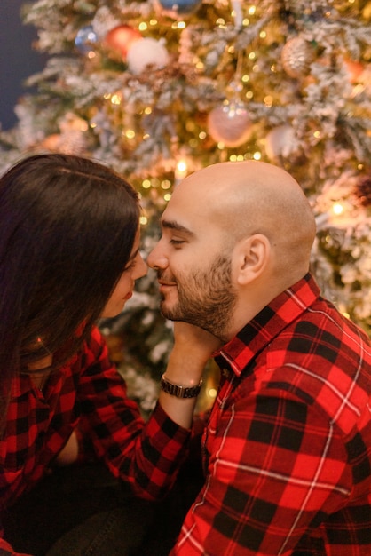 Pareja abrazándose en casa en adornos navideños