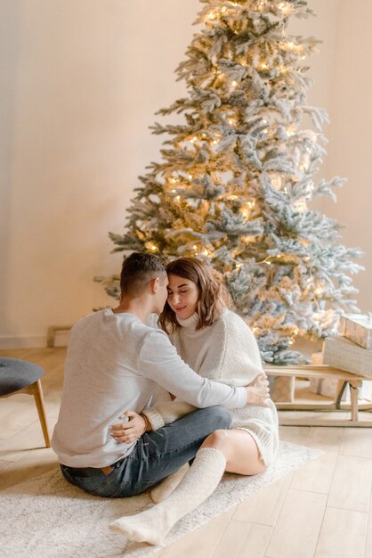 Pareja abrazándose en casa cerca de adornos navideños