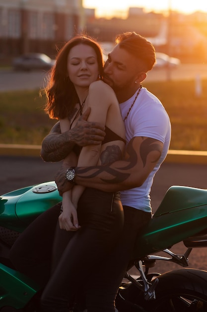 Pareja abrazándose cerca de moto al atardecer