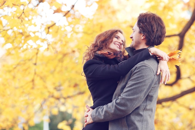 Pareja abrazándose en el parque otoño