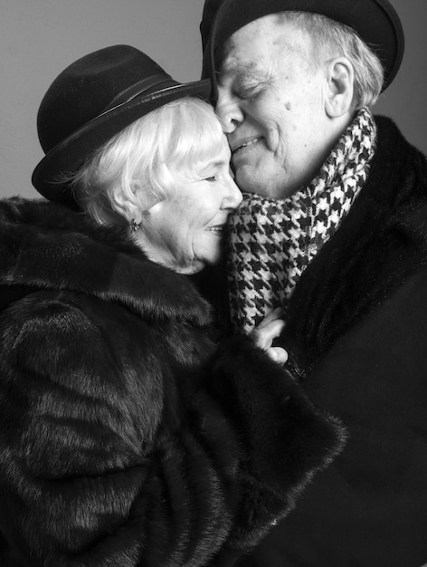 Una pareja abrazándose sonriendo contra un fondo gris