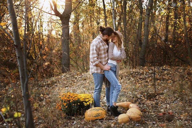 Pareja abrazos en un paseo en el otoño con calabazas