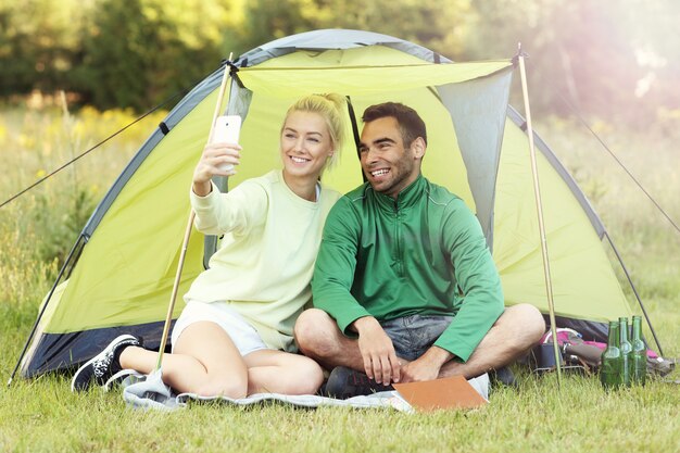 pareja acampando en el bosque y tomando selfie