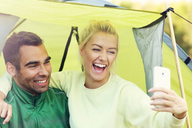 pareja acampando en el bosque y tomando selfie