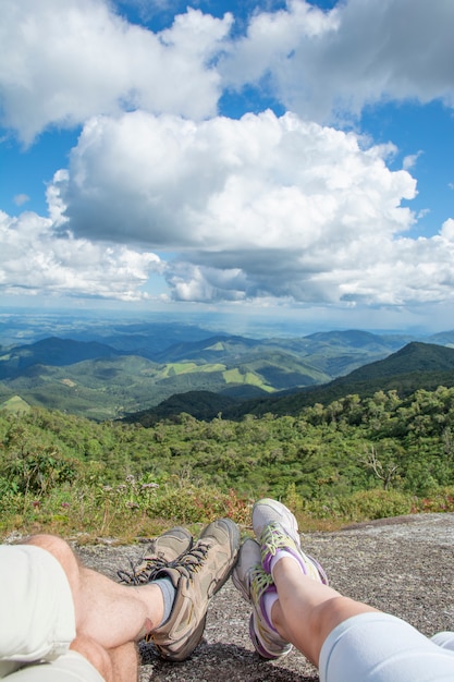 Pareja acostada sobre una roca con zapatos de trekking en una montaña.