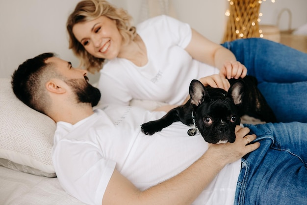 pareja, acostado, en, un, cama, con, un, bulldog francés, en, su, camisa