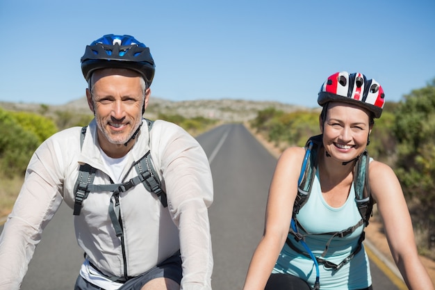 Pareja activa yendo a dar un paseo en bicicleta en el campo en un día soleado