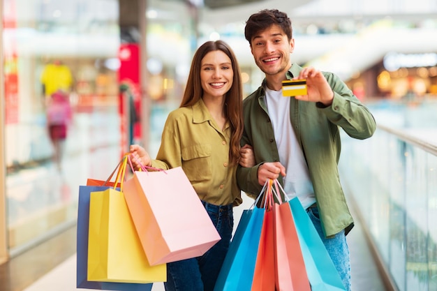 pareja, actuación, tarjeta de crédito, posar, con, shopper, bolsas, en, hipermercado