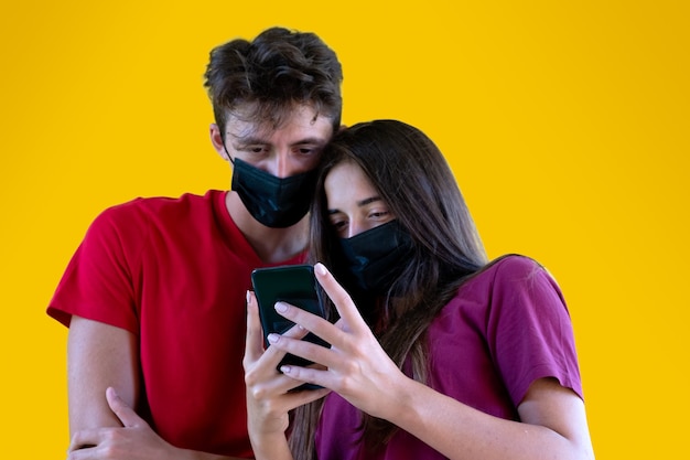 Pareja de adolescentes con smartphone sobre fondo amarillo