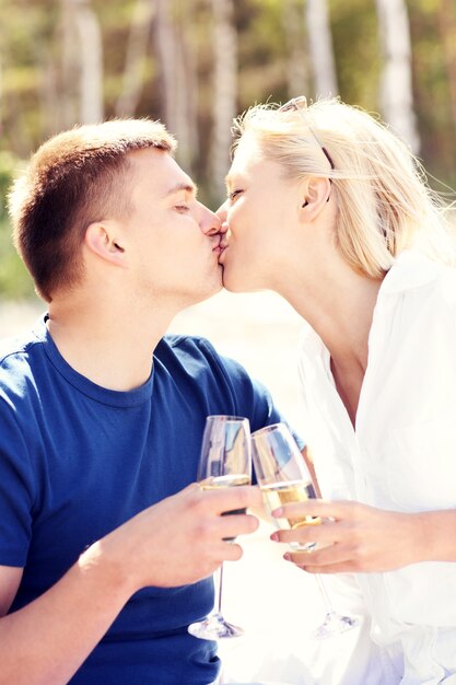 Una pareja adulta besándose en la playa con copas de champán
