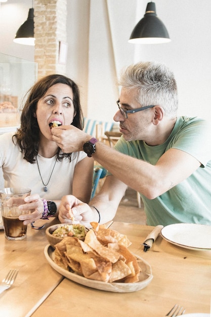 Pareja adulta disfrutando de un plato de nachos en el restaurante