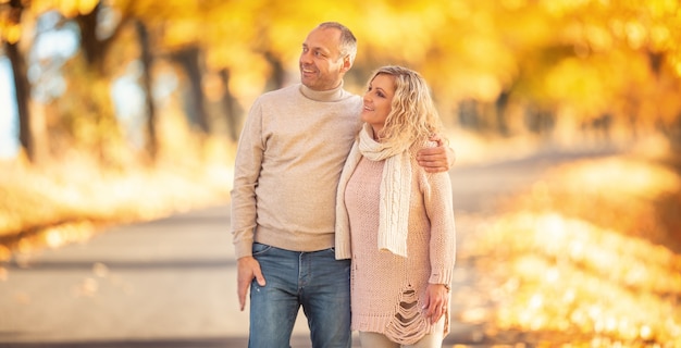 Una pareja adulta enamorada en un paseo por el callejón dorado de otoño.