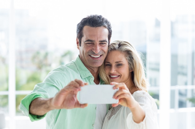 Pareja adulta media tomando selfie en casa