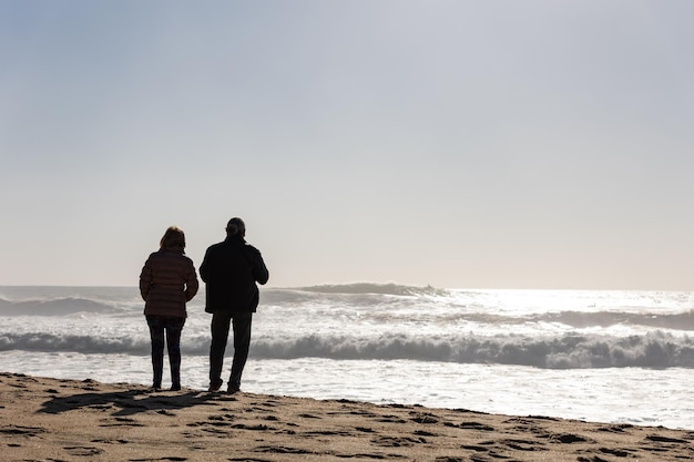 Una pareja adulta de pie en la playa y mirando el mar.