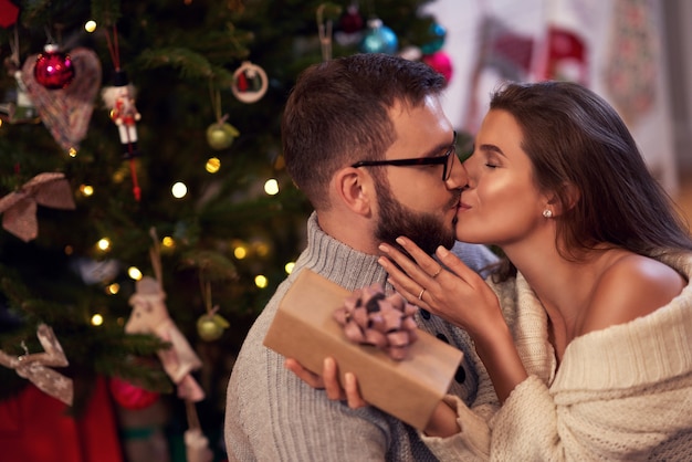 pareja adulta con presente sobre el árbol de Navidad