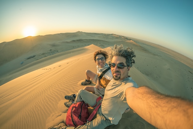 Pareja adulta tomando selfie en las dunas de arena